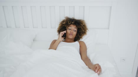 Smiling-woman-in-bed-having-phone-call