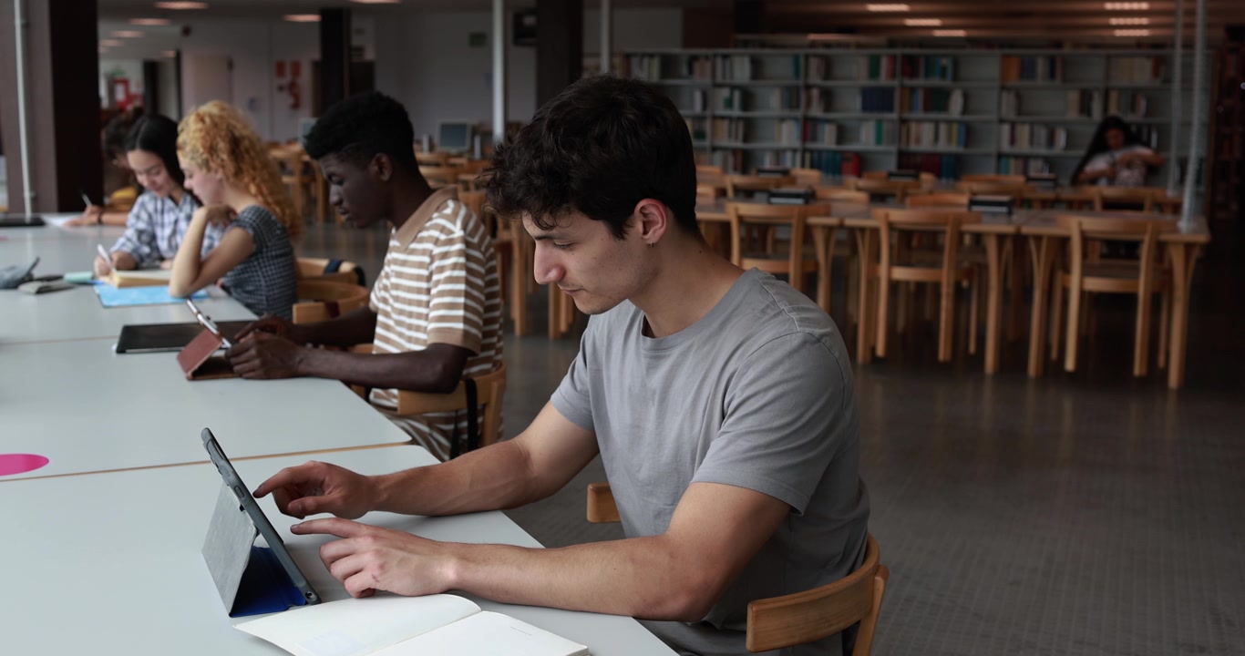 Mangfoldige studenter som studerer sammen på et universitetsbibliotek