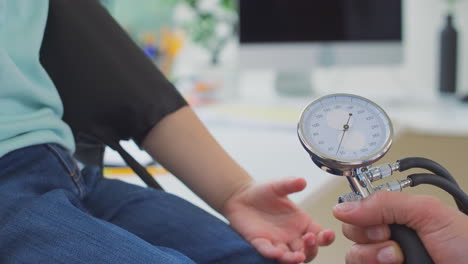 Close-Up-Of-Male-Doctor-Or-GP-Examining-Boy-Taking-Blood-Pressure-With-Sphygmomanometer