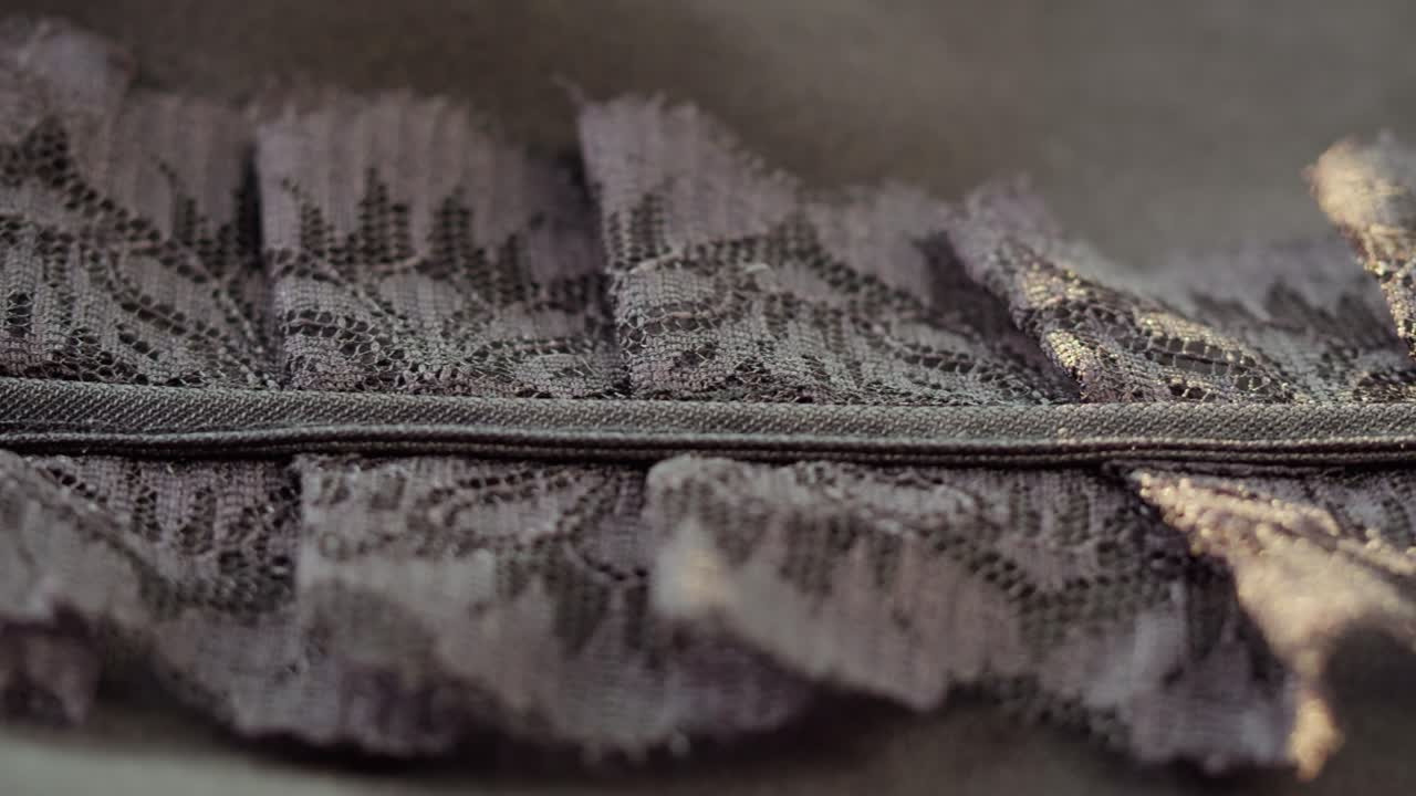 Babados de renda preta em close-up. Costura de vestido de noite em guipure. Alfaiataria artesanal, conceito de vestuário profissional. Fundo abstrato.