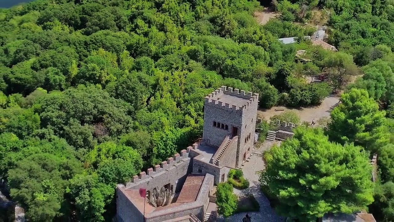 Esplorando una vecchia torre di pietra in Albania circondata da alberi verdi.