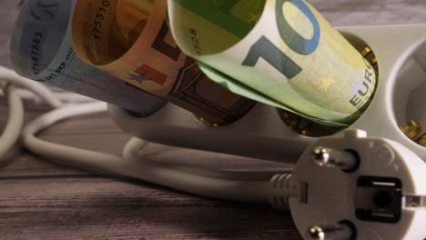 un primer plano de dinero en efectivo y un enchufe que muestra el concepto de alto precio de la electricidad.