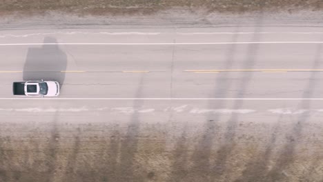 drone looking down following a white truck on the road