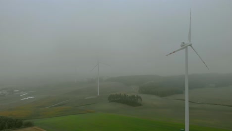 靠近風力發電廠的空中影像, 霧<unk>時的風車, 灰色風景周圍, 開放式的可再生能源, 自然風景下方, 綠色能源是重要的