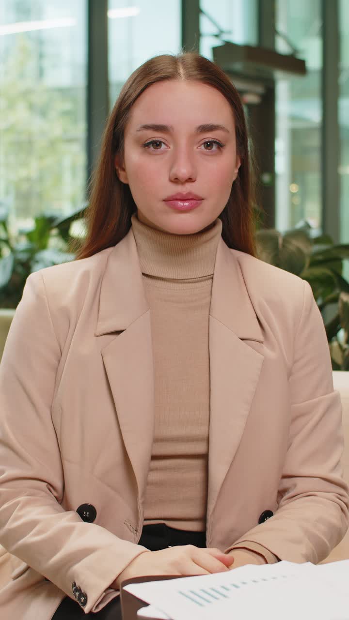 Portrait of upset caucasian businesswoman sitting in office lobby showing thumb down sign gesture