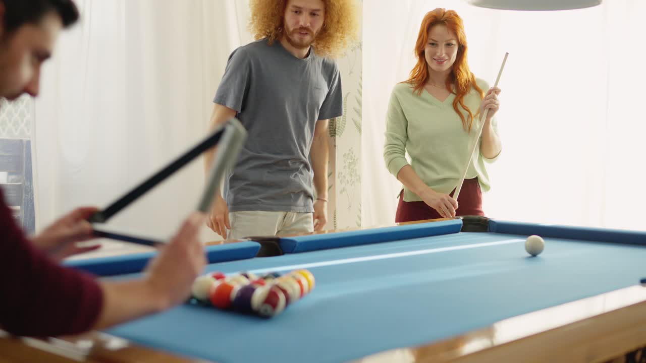Group of diverse friends playing billiards in apartment