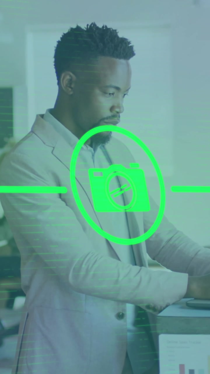 Animation of network of digital icons over african american businessman using laptop at office