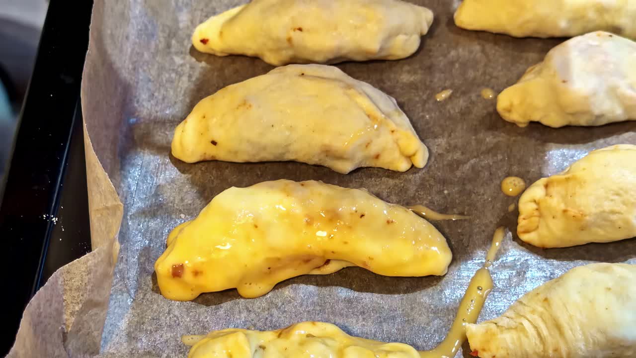 Primo piano: spennellare con burro un prodotto da forno in cucina, mano che spennella l'impasto prima della cottura.