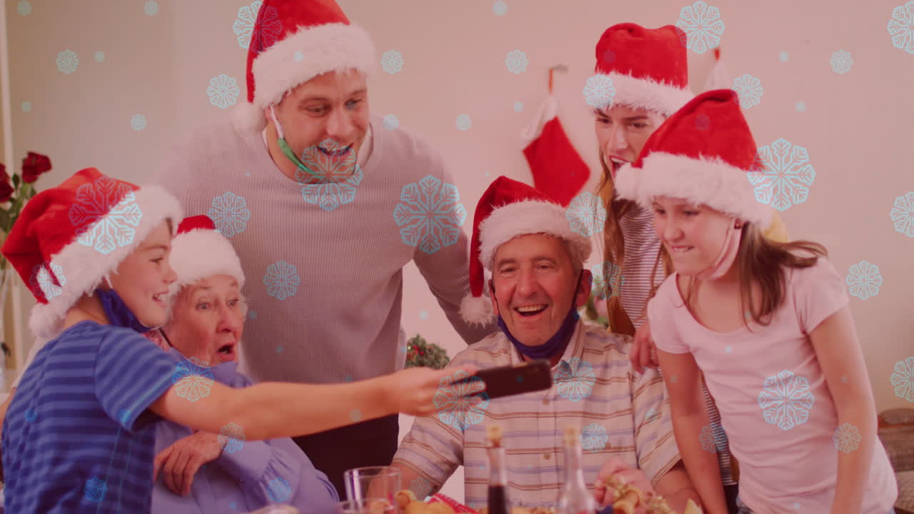 Animação de neve caindo sobre família caucasiana sorridente com gorros de Papai Noel usando smartphone