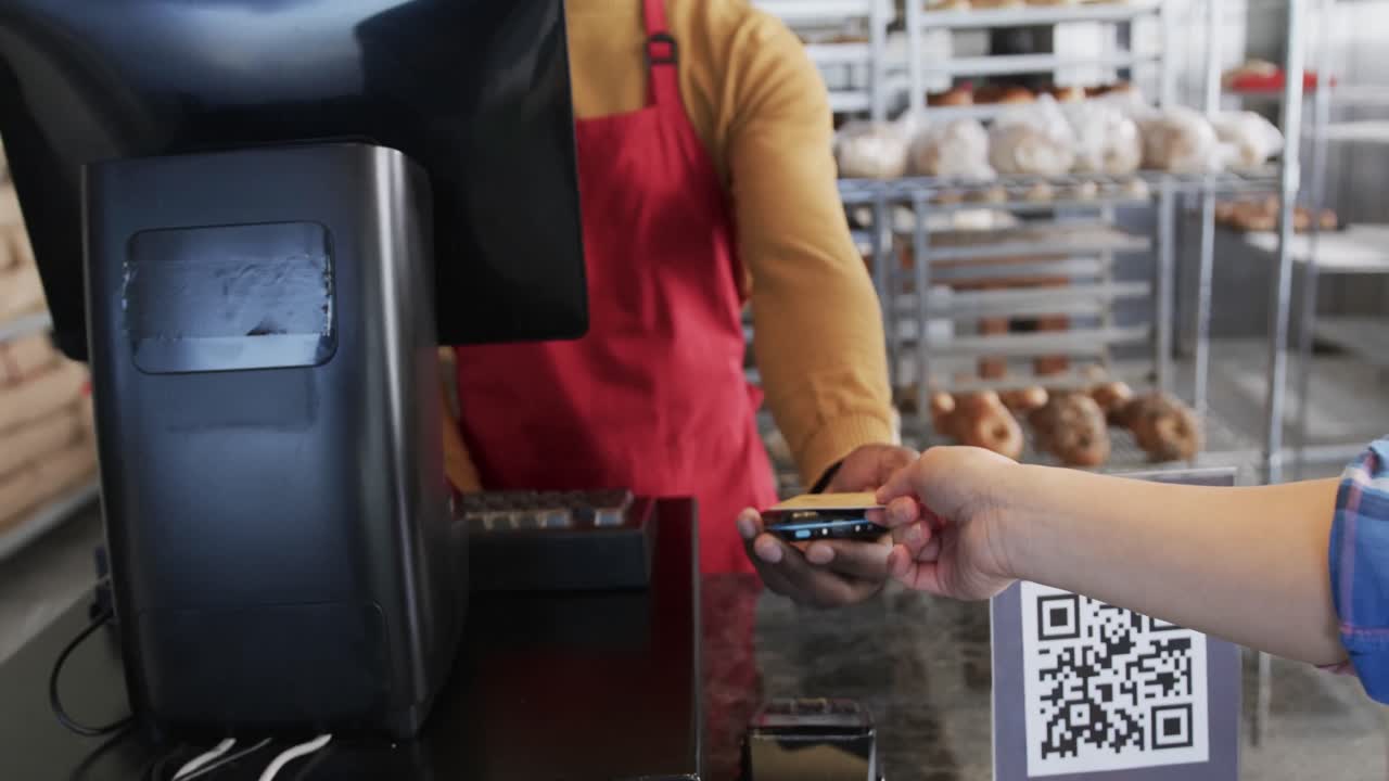 Diverse worker and customer paying with credit card in bakery in slow motion