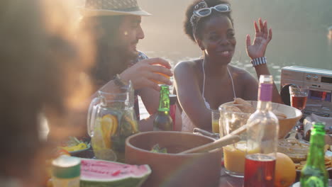 multiethnic man and woman chatting at dinner table on lake party