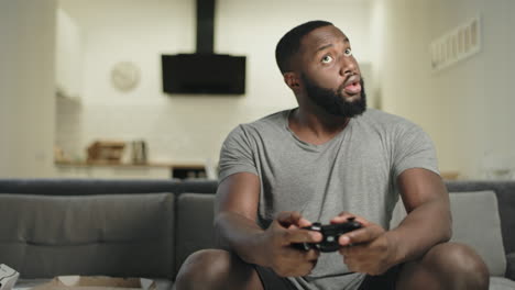 Playful-black-guy-playing-video-game-at-kitchen