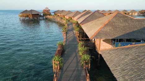 Flying-Over-Wooden-Pier-Near-Marvelous-Cottage-Houses-In-Sipadan-Village,-Malaysia