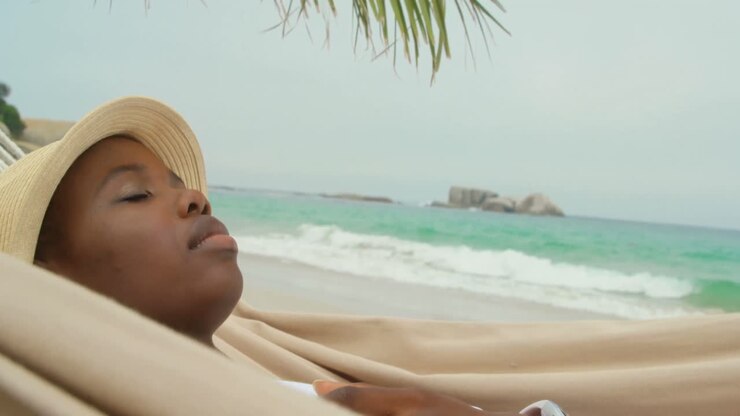 Vista laterale di una donna afroamericana che dorme in amaca in spiaggia 4k