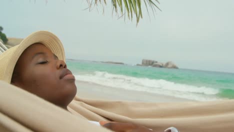 Vista-Lateral-De-Una-Mujer-Afroamericana-Durmiendo-En-Una-Hamaca-En-La-Playa-4k