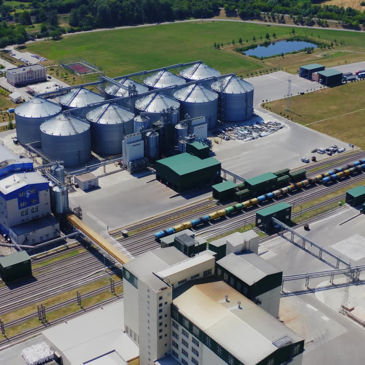 Granary for agricultural products. Flight over the aluminum containers for storing grains. Silver elevators on field. Aerial view.