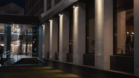 close view of a modern building exterior at night with illuminated pillars and large windows