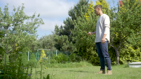 side view of caucasian young man throwing a petanque ball in the park on a sunny day