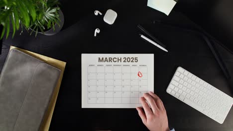 person marking a date on a march 2025 calendar