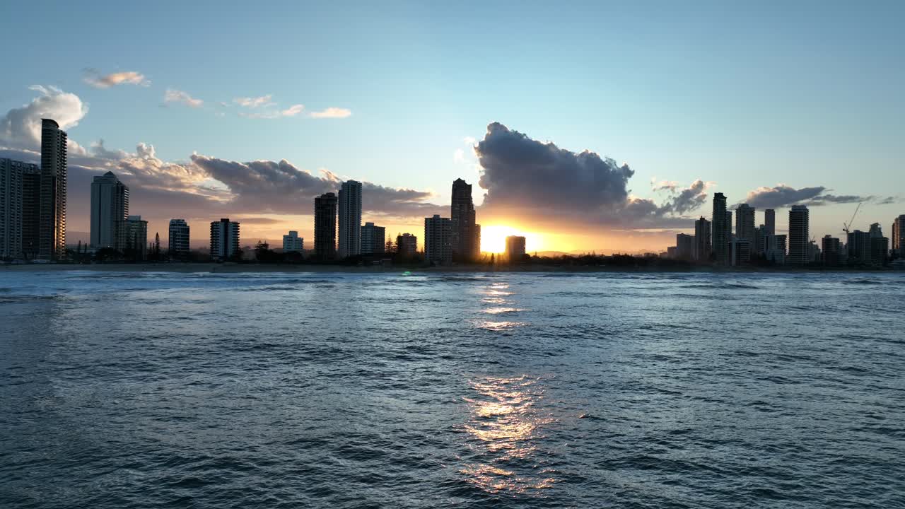 무인 항공기는 파도와 물결 모양의 물을 반사하는 태양과 함께 일몰을 향해 날아가는 바다 위로 낮게 발사되었습니다.