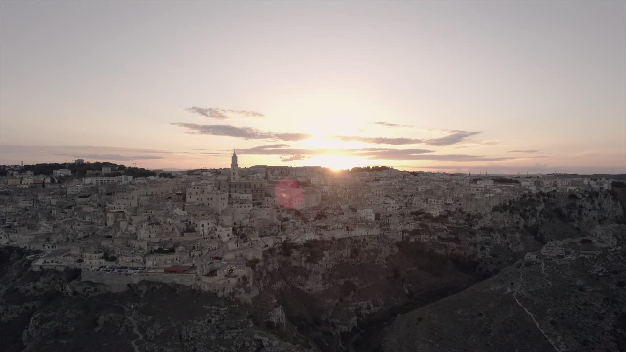 Drone che vola verso l'alto e in avanti verso l'antica città di Matera al tramonto nel sud Italia in 4K