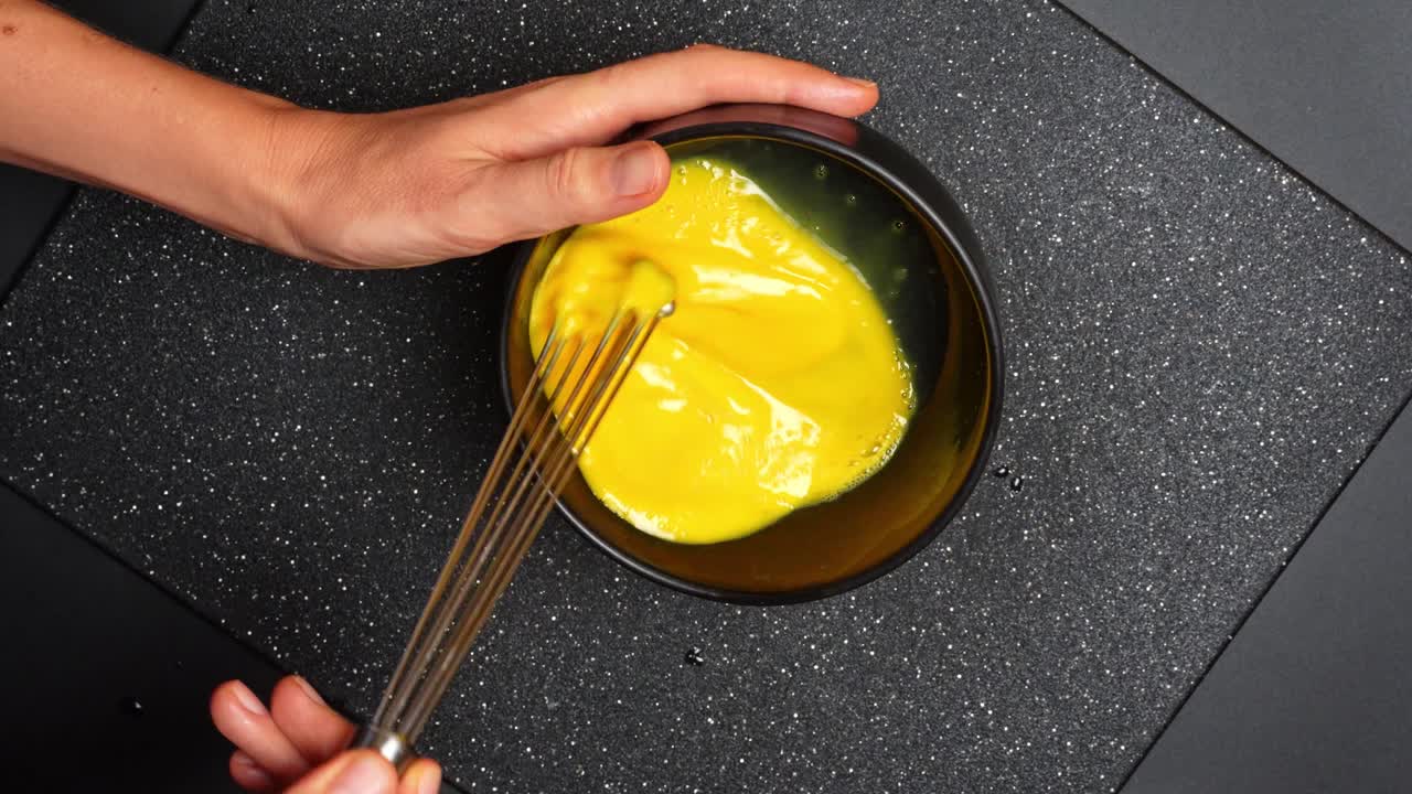 Beaten eggs texture during mixing process. Close view of beaten eggs swirling in bowl during cooking preparation