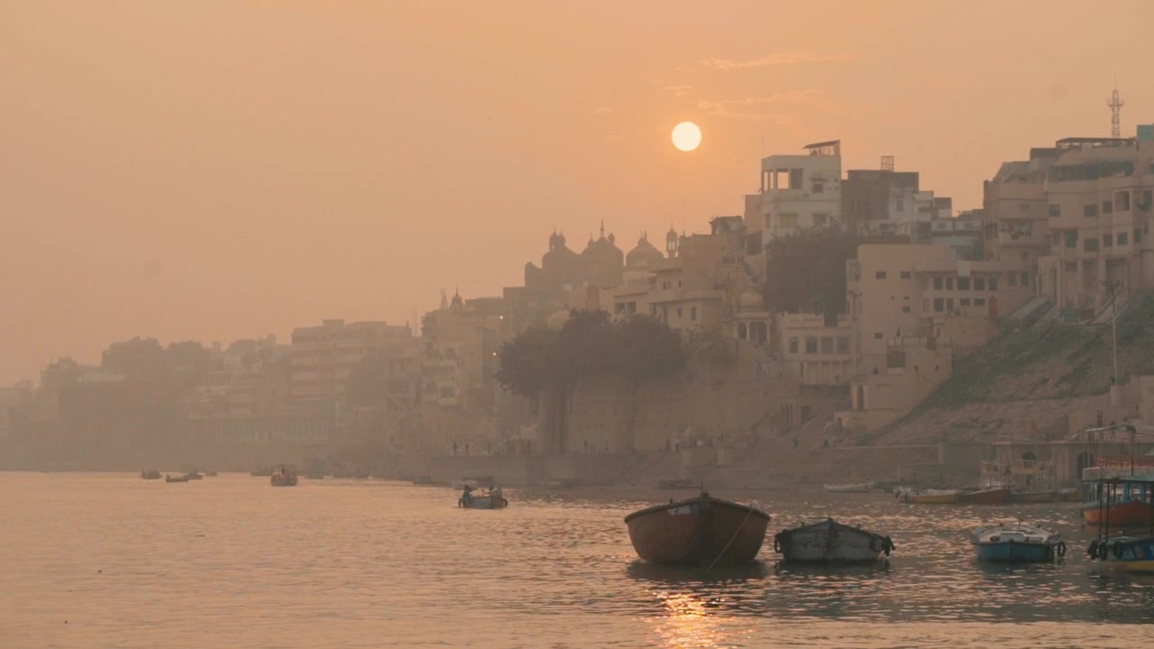 Vista di un tramonto arancione e velato di Varanasi e del fiume Gange