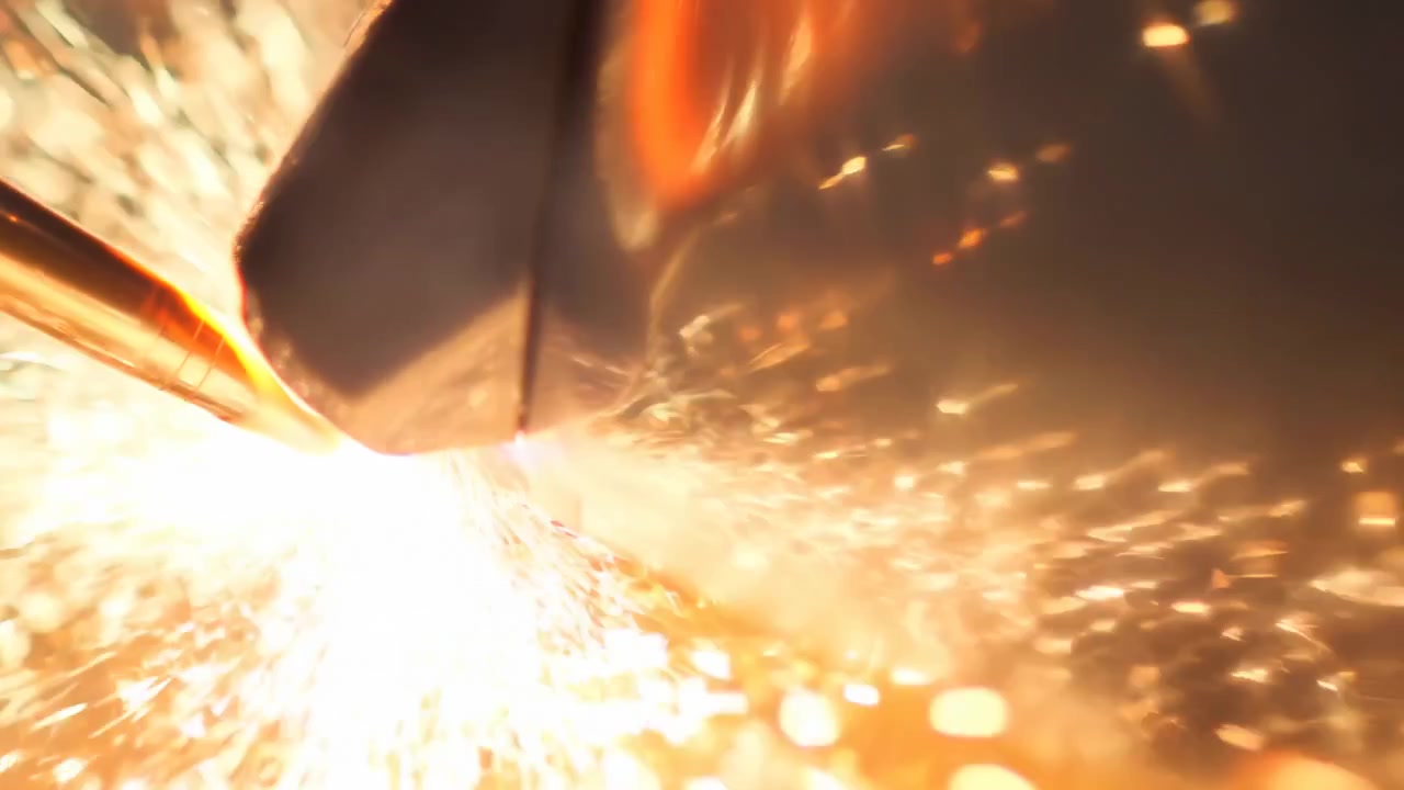 Scintille luminose schizzano da un utensile abrasivo che colpisce una superficie metallica in un'ambientazione industriale scura, con caldi riflessi arancioni, messa a fuoco ridotta e bagliori