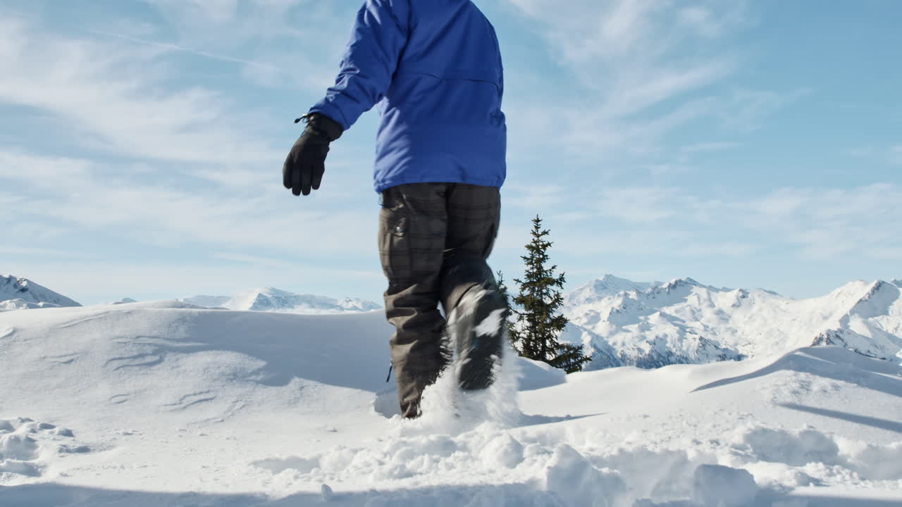 niño con traje de snowboard caminando por el ventisquero en el paisaje alpino