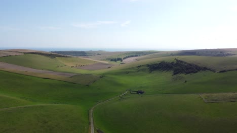 Sweeping-Drone-Shot-of-Green-Hills-and-Sea-in-the-Background,-South-Downs,-England