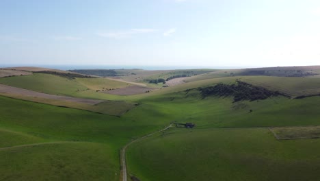 sweeping drone shot of green hills and sea in the background, south downs, england