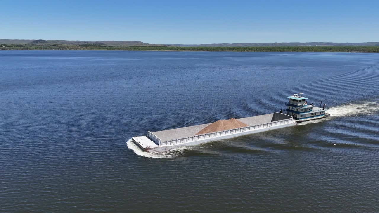 Located along the Mississippi River between Minnesota and Wisconsin's Driftless area, a towboat moves a barge filled with sand north.