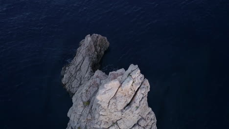 fly over drone shot of ibiza's iconic rock benirrás at sunrise