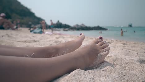 people have rest on ocean beach and sunbathing woman feet