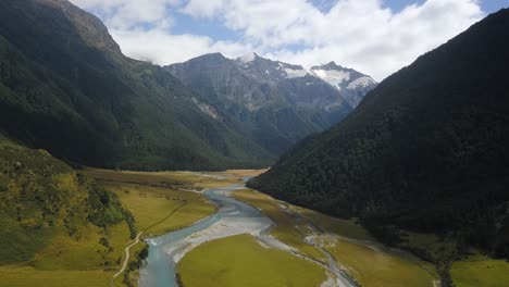 aerial view peeking around the corner of a huge valley in new zealand towards a distant glacier