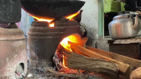 primer plano de una estufa tradicional y un fuego ardiente en el proceso de cocinar comida frita