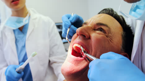dentistas examinando a un paciente masculino con herramientas