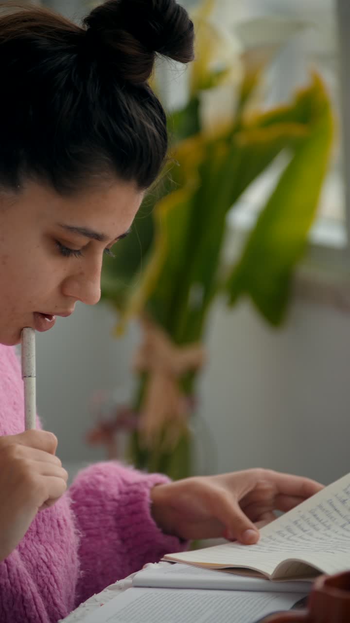 Giovane donna che scrive e studia su un quaderno a casa