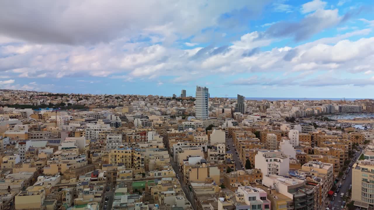 Drone orbital shot above Msida, Malta, showcasing the coastal skyline of Ta’ Xbiex, Gżira, and Sliema with urban buildings, modern towers, and Mediterranean harbor views