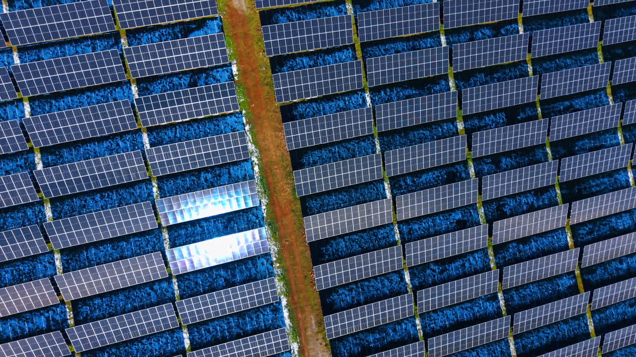 Veduta aerea ravvicinata di pannelli solari fotovoltaici blu. Vista dettagliata dall'alto di un impianto solare che riflette la luce solare con texture e motivi a griglia visibili.