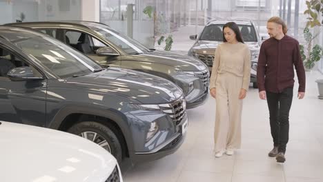 beautiful young couple at car showroom choosing a new car to buy.