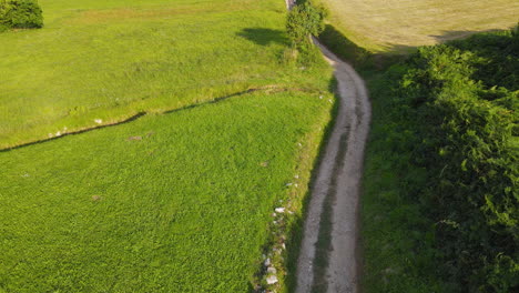 Aerial-View-Of-Group-Of-Three-Pilgrims-Walking-Together-On-Dirt-Road-On-A-Sunny-Day