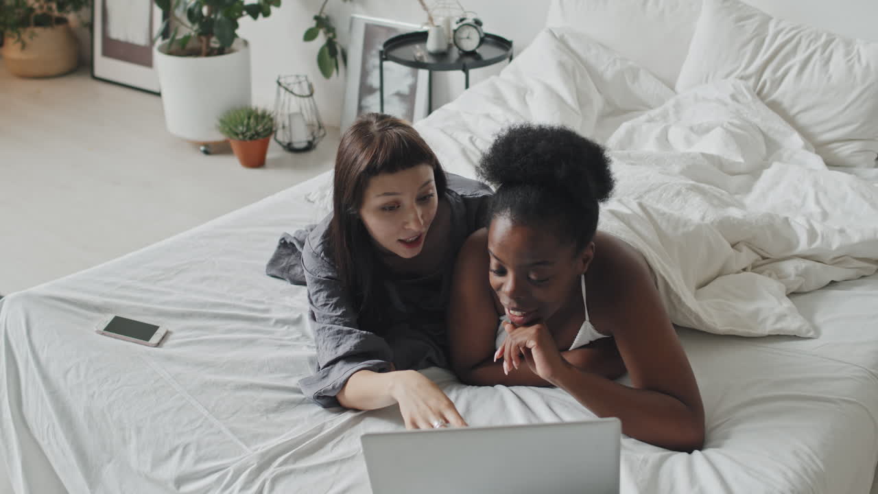 Affectionate Lesbian Couple with Laptop Lying on Bed