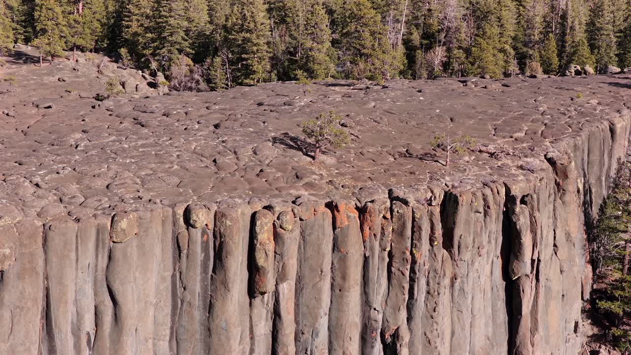 Luonnonkivirakenteiset urkupillit luovat rytmisen pystysuoran tekstuurin aavikon horisonttia vasten. Tämä 4K-materiaali vangitsee muinaisen geologian karun kauneuden ja yksinäisen eloonjääneen puun.