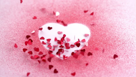 animation of red hearts falling over pink powder forming white heart