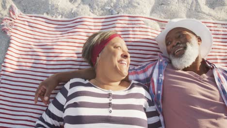 Glückliches-älteres-Afroamerikanisches-Paar,-Das-Auf-Einer-Decke-Am-Strand-Liegt,-Zeitlupe