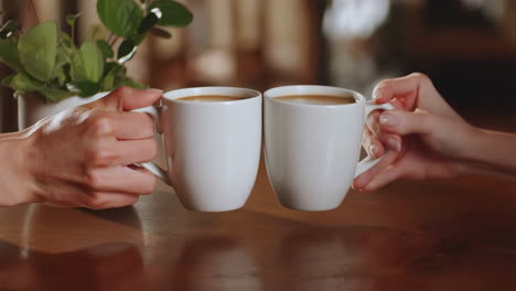 two hands clinking coffee mugs