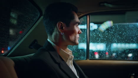 elegante abogado descansando automóvil noche ciudad primer plano. hombre mirando ventana lluviosa