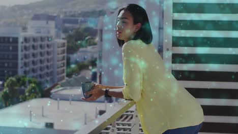 animation of light spots over biracial woman drinking coffee on balcony