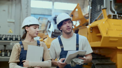 maintenance technician discussing machinery with female colleague in factory